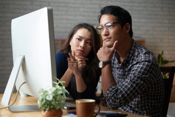 Professionals discussing business strategy in front of a desktop computer.